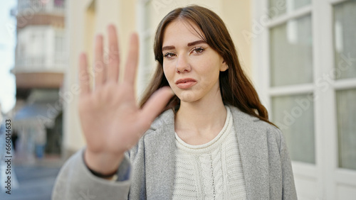 Young hispanic woman doing stop gesture with hand at street