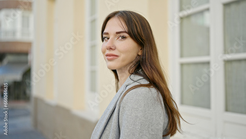 Young hispanic woman standing with serious expression looking to the side at street
