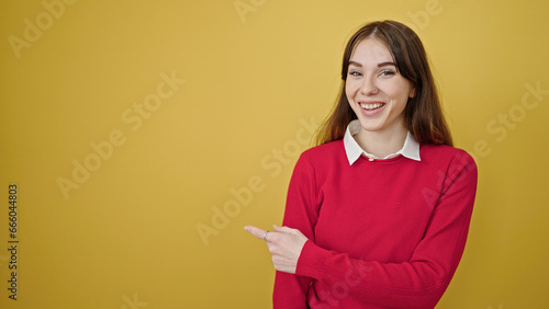 Young hispanic woman smiling pointing to the side over isolated yellow background © Krakenimages.com