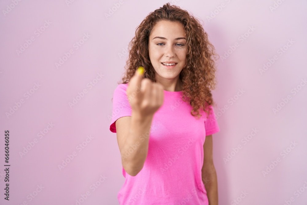 Young caucasian woman standing over pink background beckoning come here gesture with hand inviting welcoming happy and smiling Young caucasian woman standing over pink background beckoning come here gesture with hand inviting welcoming happy and smiling