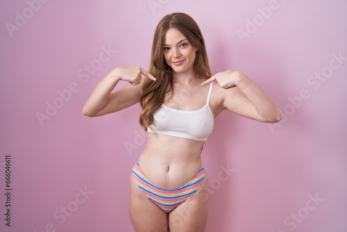 Caucasian woman wearing lingerie over pink background looking confident with smile on face, pointing oneself with fingers proud and happy. © Krakenimages.com