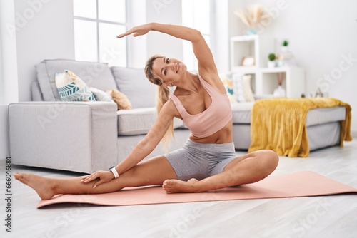 Young blonde woman smiling confident stretching back at home