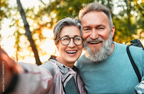 Wonderful sincere cheerful couple of gray haired mature smiling people taking selfie portrait on phone. Today's active retirees are enjoying life. A man with a gray beard and a woman in glasses. photo