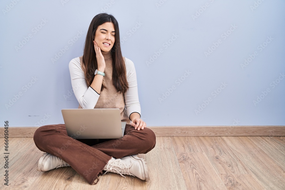 Young brunette woman working using computer laptop sitting on the floor touching mouth with hand with painful expression because of toothache or dental illness on teeth. dentist concept. Young brunette woman working using computer laptop sitting on the floor touching mouth with hand with painful expression because of toothache or dental illness on teeth. dentist concept.