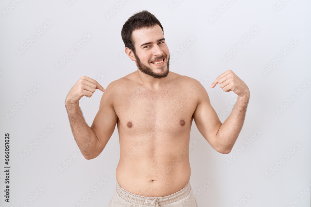 Young hispanic man standing shirtless over white background looking confident with smile on face, pointing oneself with fingers proud and happy.