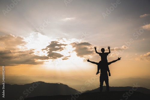 Silhouette of a boy riding on his father's neck Nature amidst the sunset light happy holiday concept Happy family.