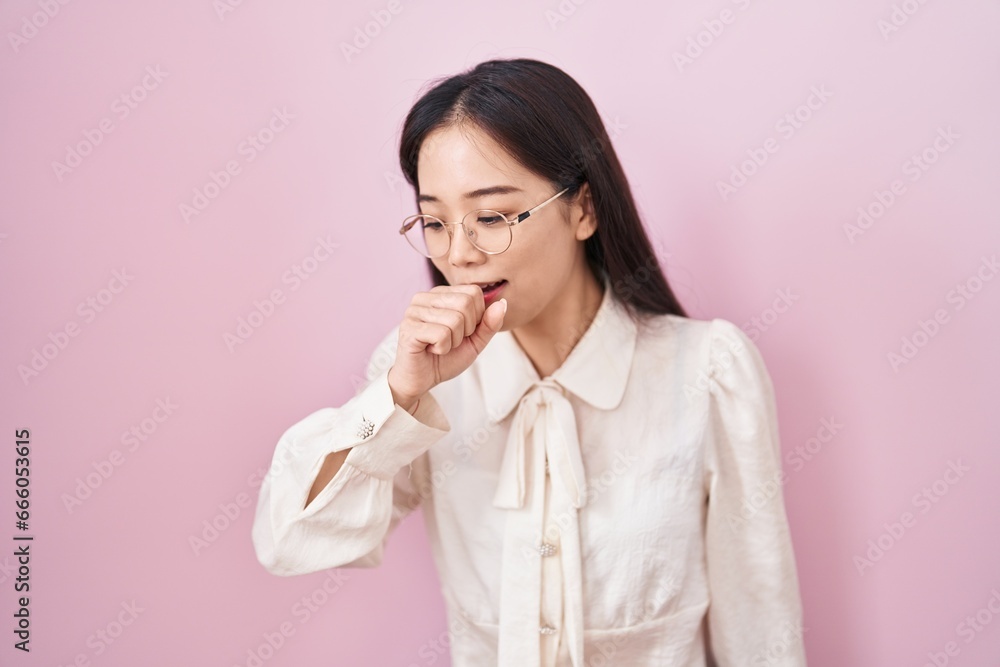 Young chinese woman standing over pink background feeling unwell and coughing as symptom for cold or bronchitis. health care concept. Young chinese woman standing over pink background feeling unwell and coughing as symptom for cold or bronchitis. health care concept.