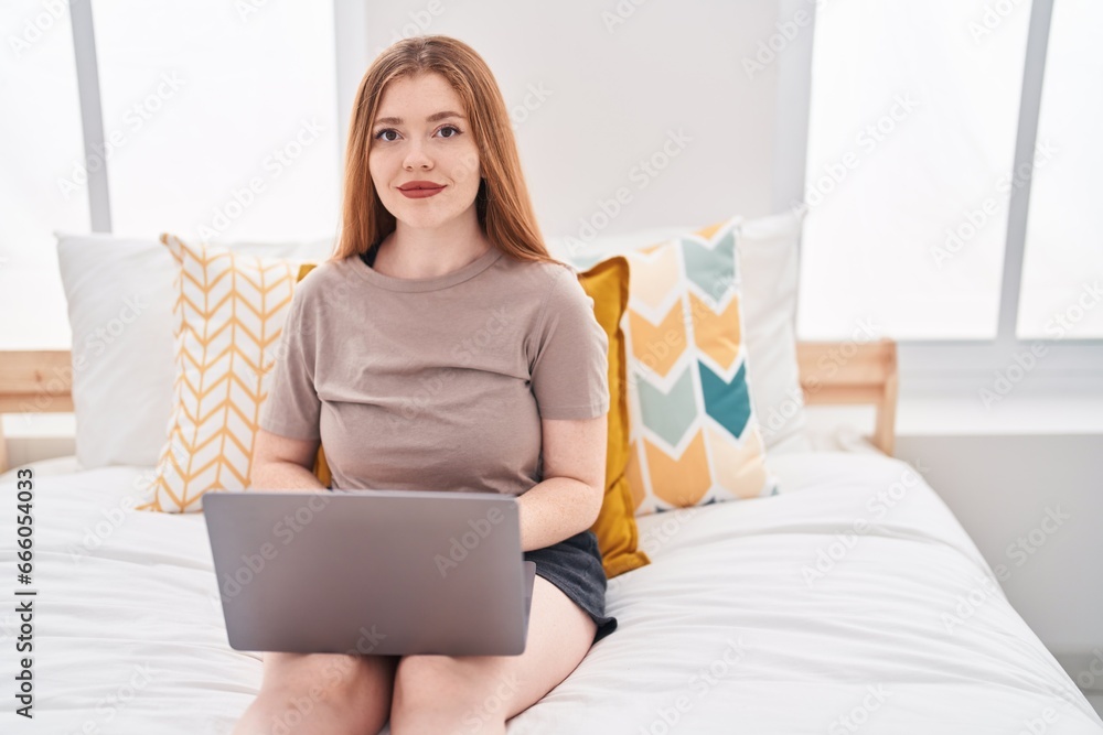 Young redhead woman using laptop sitting on bed at bedroom Young redhead woman using laptop sitting on bed at bedroom