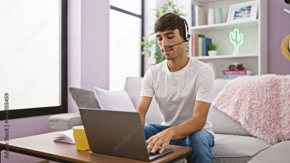 Young hispanic man call center agent using laptop and headphones sitting on sofa at home Young hispanic man call center agent using laptop and headphones sitting on sofa at home