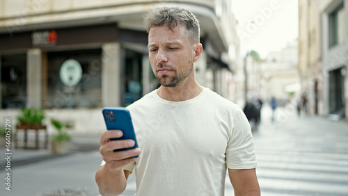 Young man using smartphone with serious expression at street