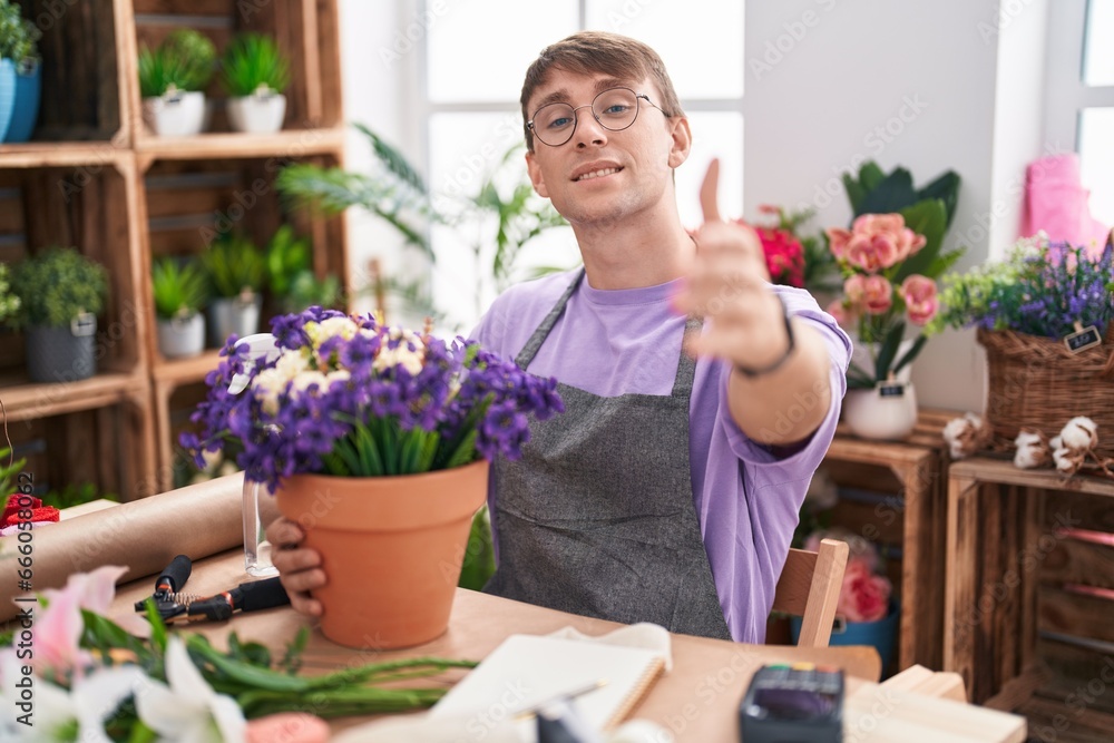 Caucasian blond man working at florist shop smiling friendly offering handshake as greeting and welcoming. successful business.