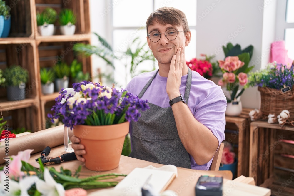Caucasian blond man working at florist shop touching mouth with hand with painful expression because of toothache or dental illness on teeth. dentist concept.