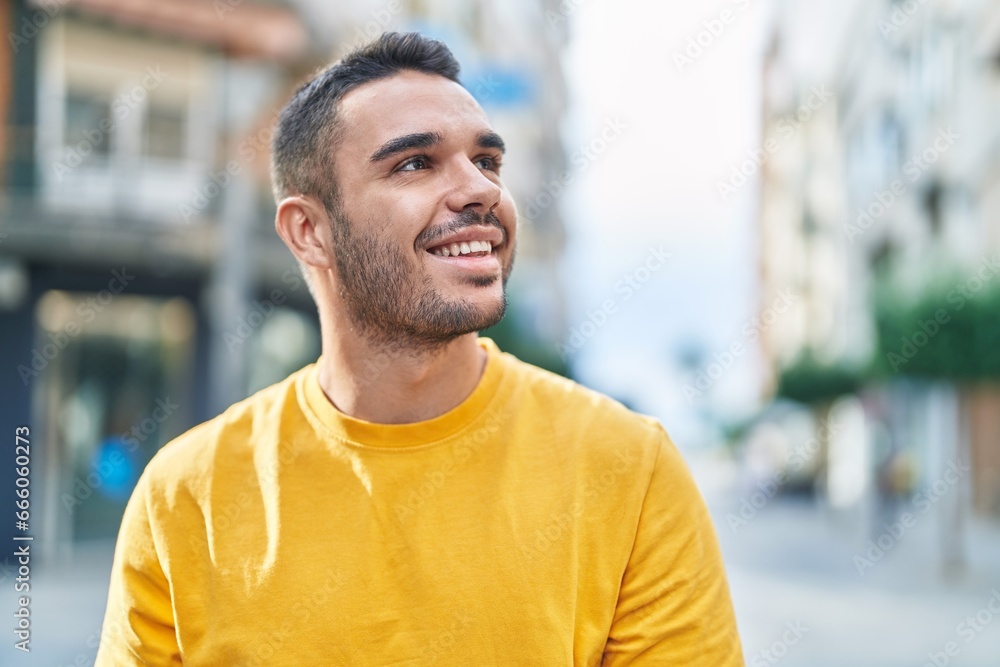 Fototapeta premium Young hispanic man smiling confident looking to the sky at street