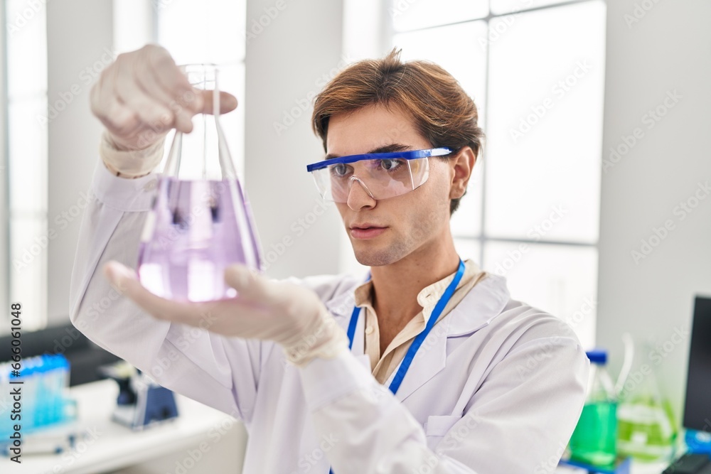 Young caucasian man scientist looking test tube at laboratory Young caucasian man scientist looking test tube at laboratory