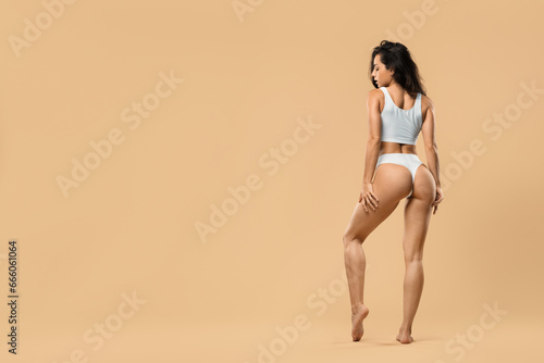 Perfect body shape. Woman posing in white underwear over beige studio background © Prostock-studio