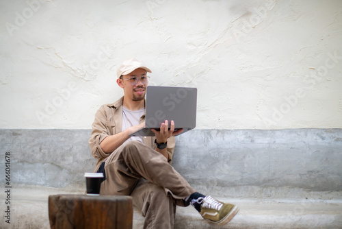 Freelance man wearing a cap having a relaxed video call in an online meeting using a laptop.