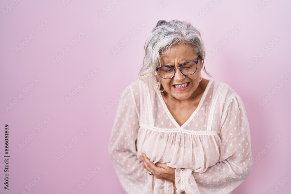 Φωτογραφία Middle age woman with grey hair standing over pink background with hand on stomach because nausea, painful disease feeling unwell