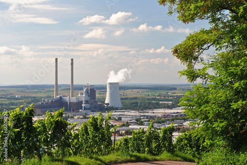 View of Cooling Tower and Industrial Chimneys from Tree Covered Hill on Sunny Day photo