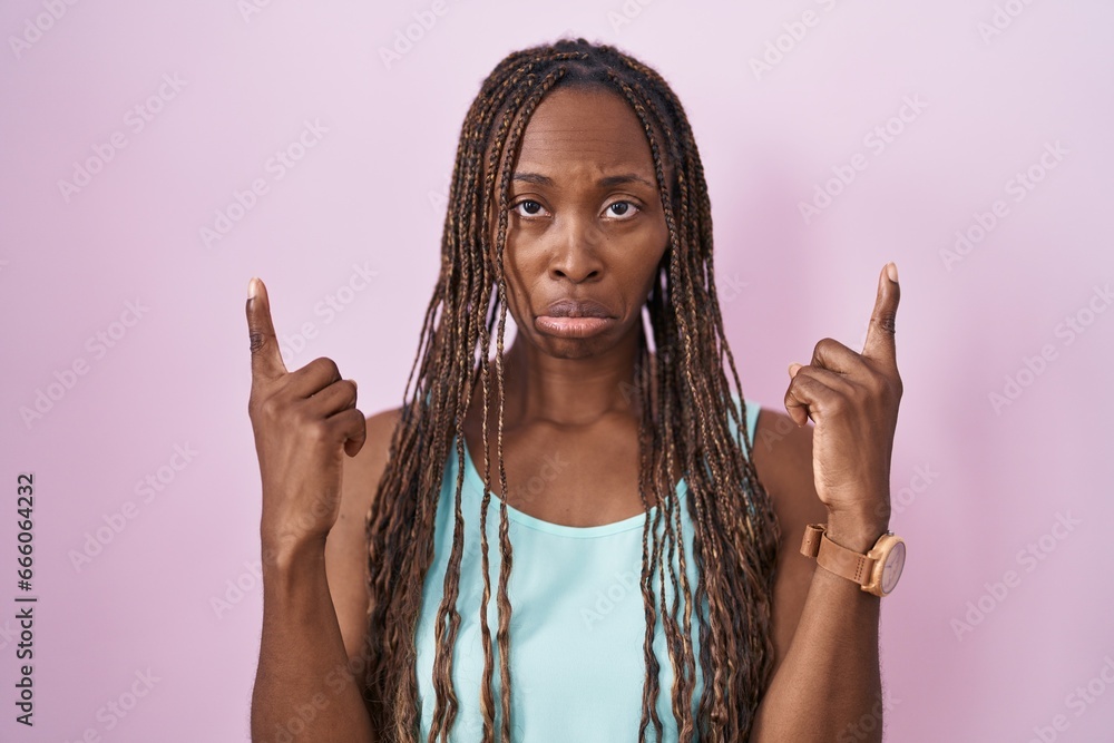 Φωτογραφία African american woman standing over pink background pointing up looking sad and upset, indicating direction with fingers, unhappy and depressed
