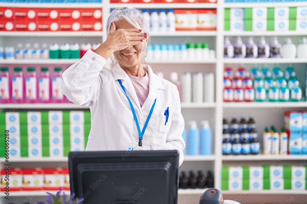 Middle age woman with tattoos working at pharmacy drugstore smiling and laughing with hand on face covering eyes for surprise. blind concept. Middle age woman with tattoos working at pharmacy drugstore smiling and laughing with hand on face covering eyes for surprise. blind concept.