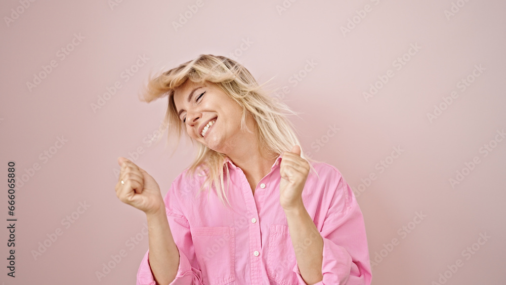 Young blonde woman smiling confident dancing over isolated pink background