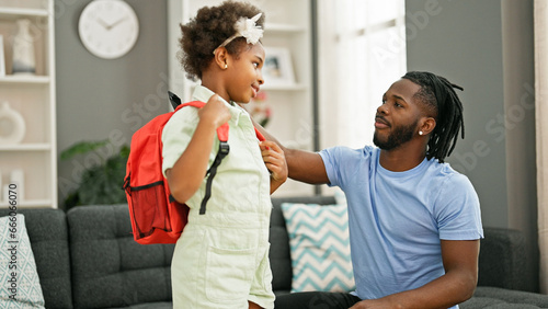 African american father and daughter wearing backpack preparing to go to school at home