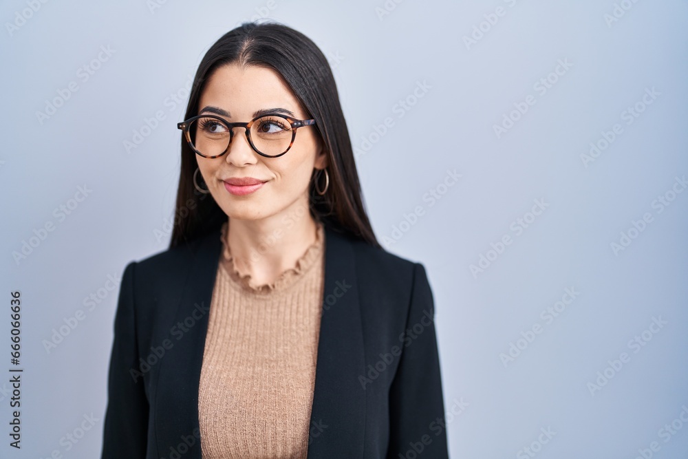 Young brunette woman standing over blue background smiling looking to the side and staring away thinking. Young brunette woman standing over blue background smiling looking to the side and staring away thinking.