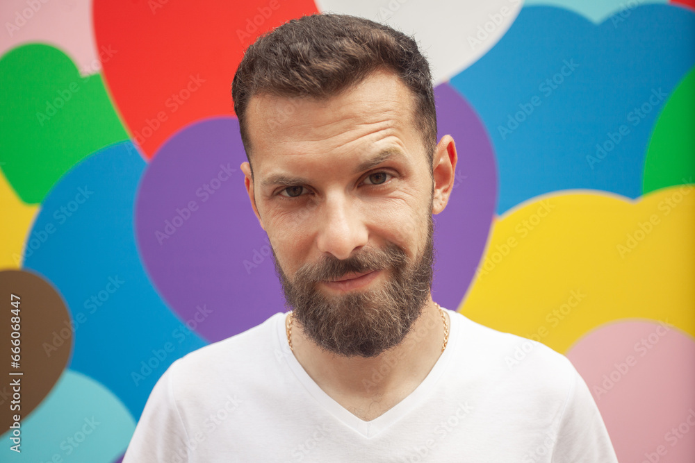 Fototapeta premium Love concept. Portrait of proud charismatic active 30-year-old man posing over colourful background. Perfect haircut. Hipster style. Close up. Outdoor shot