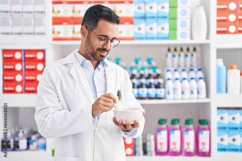 Young hispanic man pharmacist smiling confident working at pharmacy