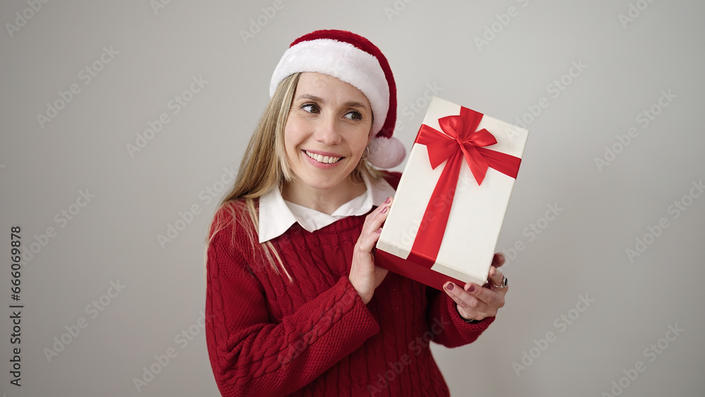Φωτογραφία Young blonde woman wearing christmas hat hearing sound gift at street