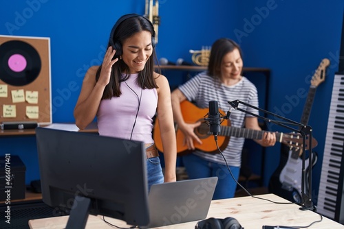 Two women musicians playing classical guitar using laptp at music studio