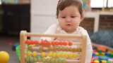 Adorable toddler playing with abacus sitting on floor at kindergarten