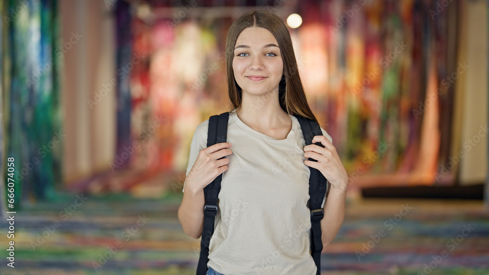 Fototapeta premium Young beautiful girl student smiling confident wearing backpack at art gallery