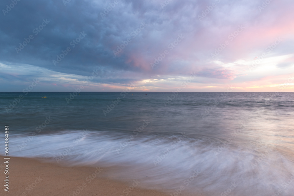 Obraz premium Sunset on sandy beach with ocean waves and colorful sky and clouds, Algarve, Portugal