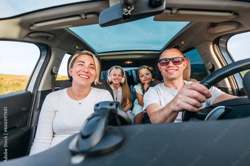 © Soloviova Liudmyla - A happy young couple with two daughters inside the car during auto trop. They are smiling, and laughing during a road trip. Family values, traveling concepts. © Soloviova Liudmyla - A happy young couple with two daughters inside the car during auto trop. They are smiling, and laughing during a road trip. Family values, traveling concepts.