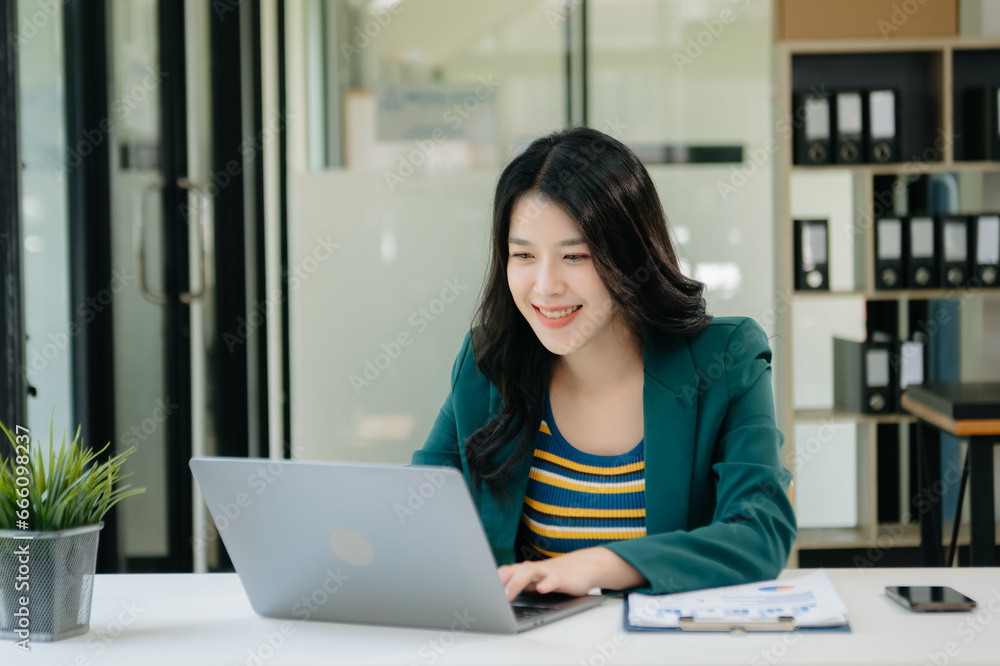 Beautiful Asian business woman typing laptop and tablet Placed at the table at the office. Beautiful Asian business woman typing laptop and tablet Placed at the table at the office.