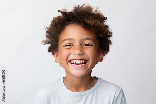 A professional portrait studio photograph featuring an adorable, mixed-race young boy with immaculately clean teeth, radiating joy with laughter and smiles. This image is isolated on white background