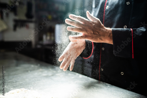 Closeup of chef's hands sprinkling flour