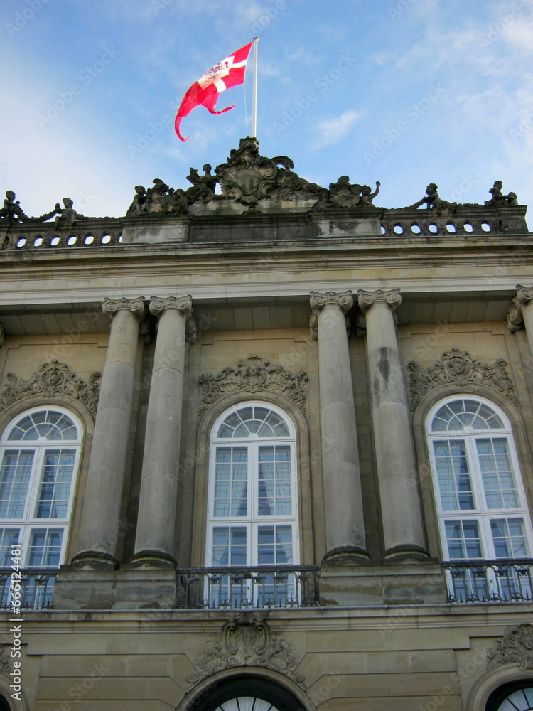 antique gray building with columns and a flag on top in Copenhagen, Denmark