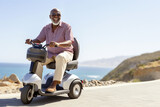 Elderly African American man on a mobility scooter on the sea cost, senior enjoying the beach