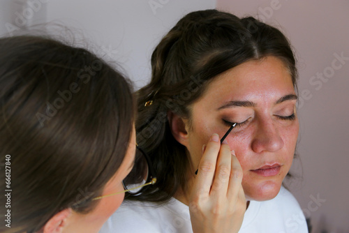 Close up of a make up artist doing bridal makeup on beautiful caucasian woman with brunette hair