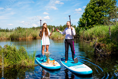 Young attractive couple on stand up paddle board in the lake, SUP