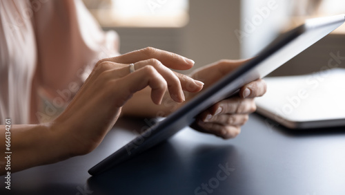 Close up arm businesswoman holds tablet computer working using internet business app seated at desk, housewife makes order do household routine, browse web, search recipe, check social network concept photo