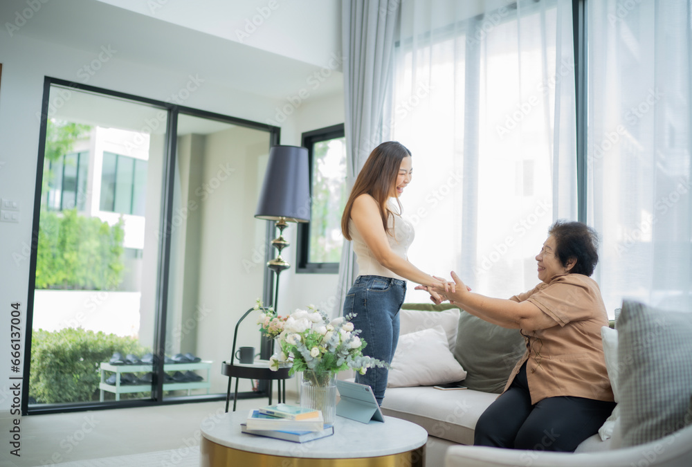 Loving adult daughter touching older mother, hands standing at couch at home, family enjoying tender moment together, young woman and mature mum or grandmother looking at each other, two generations Loving adult daughter touching older mother, hands standing at couch at home, family enjoying tender moment together, young woman and mature mum or grandmother looking at each other, two generations
