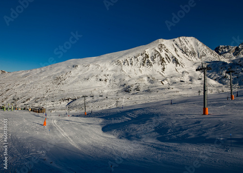 Foto Paisagem de montanhas ao fundo e neve branca no chão e céu azul.