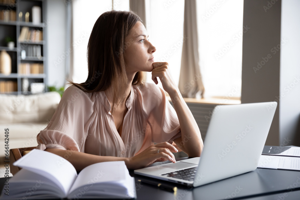 Pensive woman sit at table thinking looking out the window, housewife solve household issues using laptop personal organizer. Business lady makes decision distracted from typing email lost in thoughts Pensive woman sit at table thinking looking out the window, housewife solve household issues using laptop personal organizer. Business lady makes decision distracted from typing email lost in thoughts