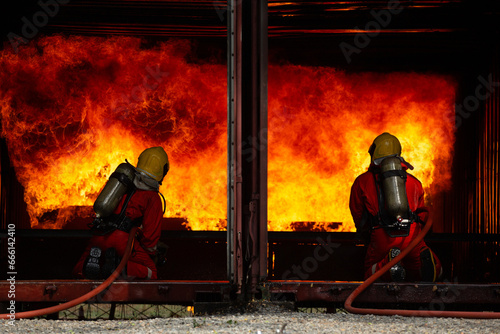 Burning cargo container, Fireman water spray by high pressure nozzle in fire fighting operation, Fire Firefighter training school, Firefighters fight oil and gas flames to control fires from spreading