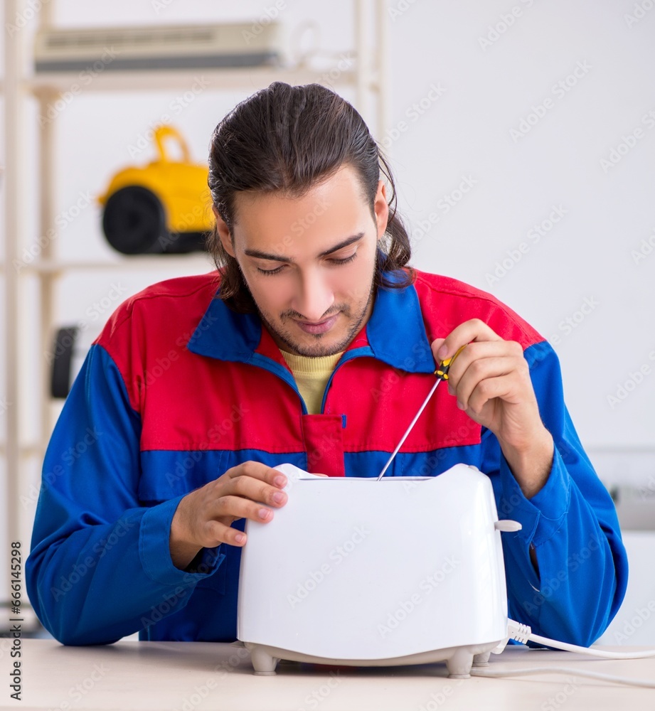 Young male contractor repairing toaster at workshop Young male contractor repairing toaster at workshop