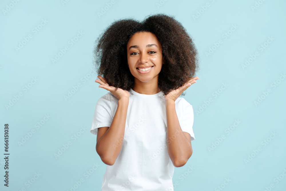 Happy authentic african american woman with curly hair wearing white t shirt looking at camera Happy authentic african american woman with curly hair wearing white t shirt looking at camera