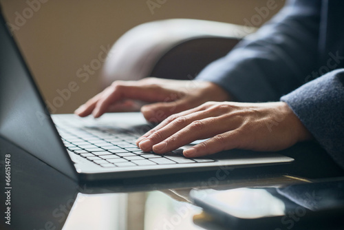 Close-up of businesswoman typing on laptop and doing her online work while sitting in the hotel